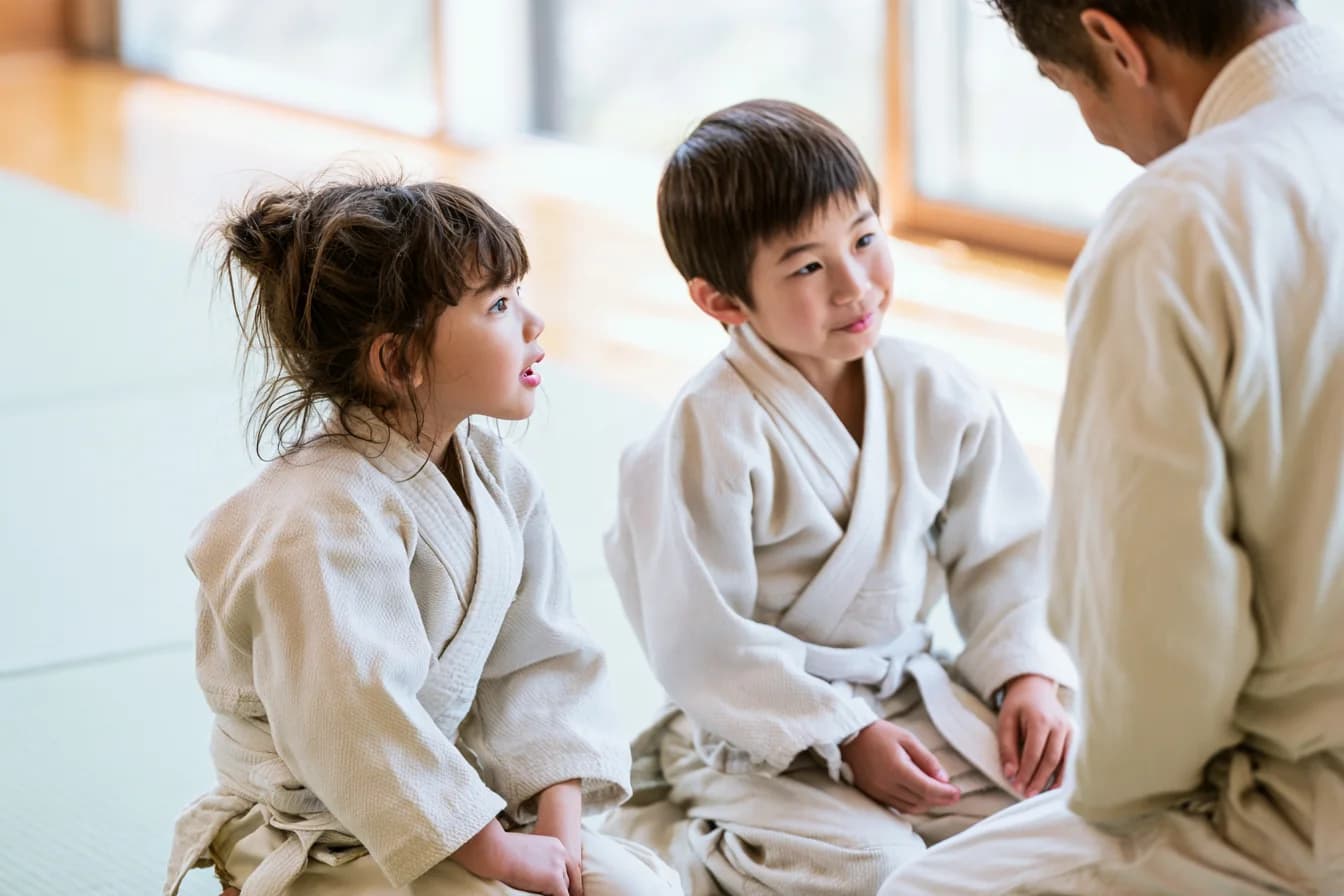 道場で先生と向き合う、柔道着の子どもたち
